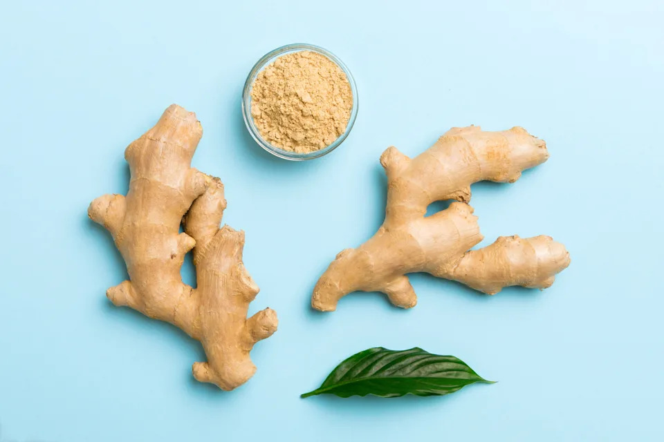 Finely dry Ginger powder in bowl with green leaves isolated on colored background. top view flat lay.