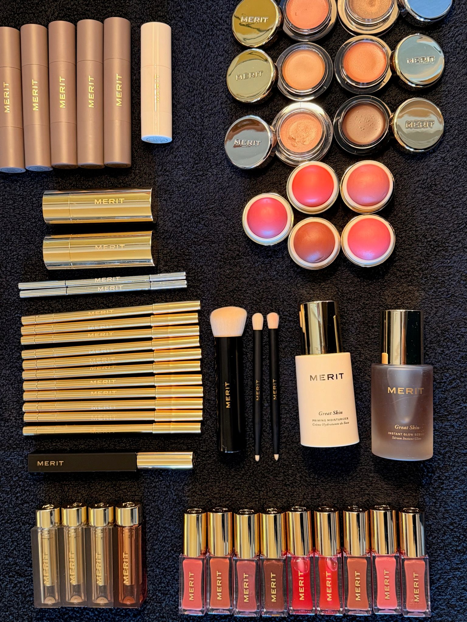 A flatlay of Merit beauty products laid out on top of a black towel.