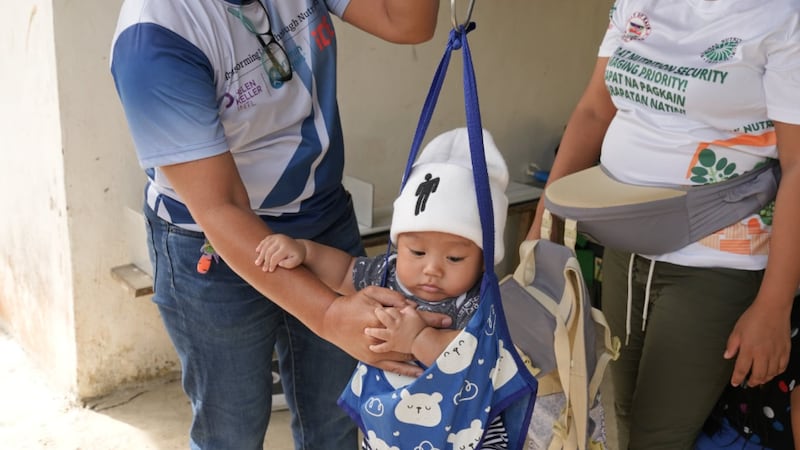 A child is weighed during a nutritional screening in the Philippines, August 2025.