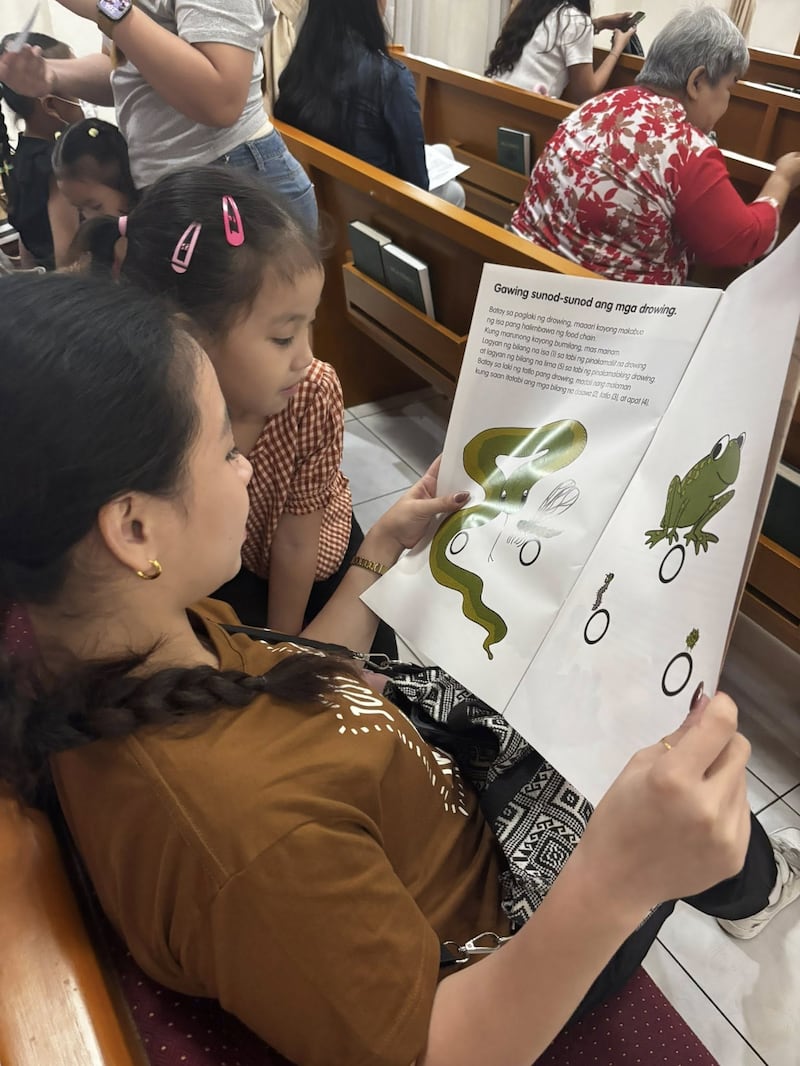A mother and child read a book about nutrition during the first Child Nutrition Program screening held at the Caloocan Philippines Stake Center on Jan. 24, 2026.