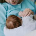 A mother holds her newborn baby in a hospital bed.