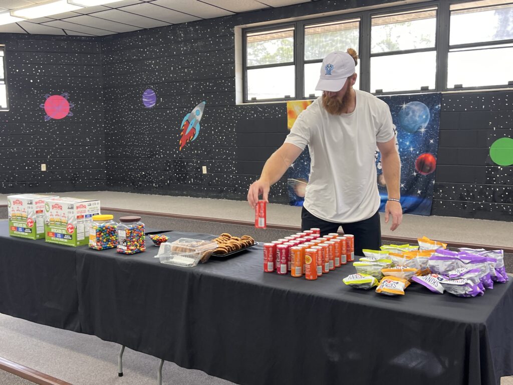 Hayden Hurst places a drink on a table for the Teacher Appreciation Recharge Station. Photo by Nick Anschultz