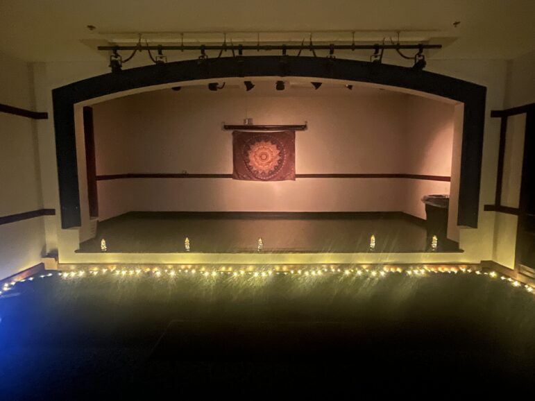 Stage set with Inner Fire Flow logo on a banner and fake candles around the theater