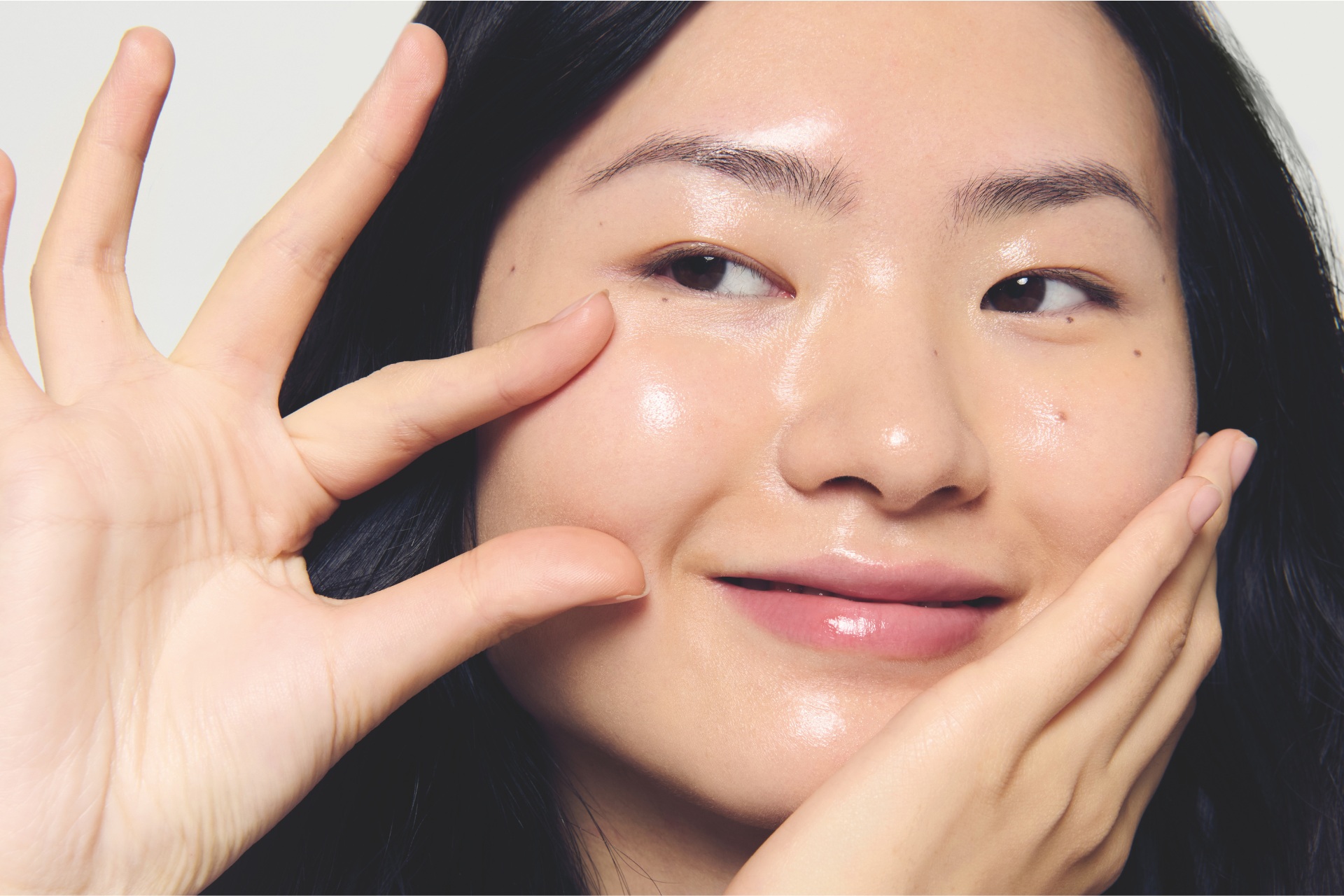 Asian woman pinching own cheek