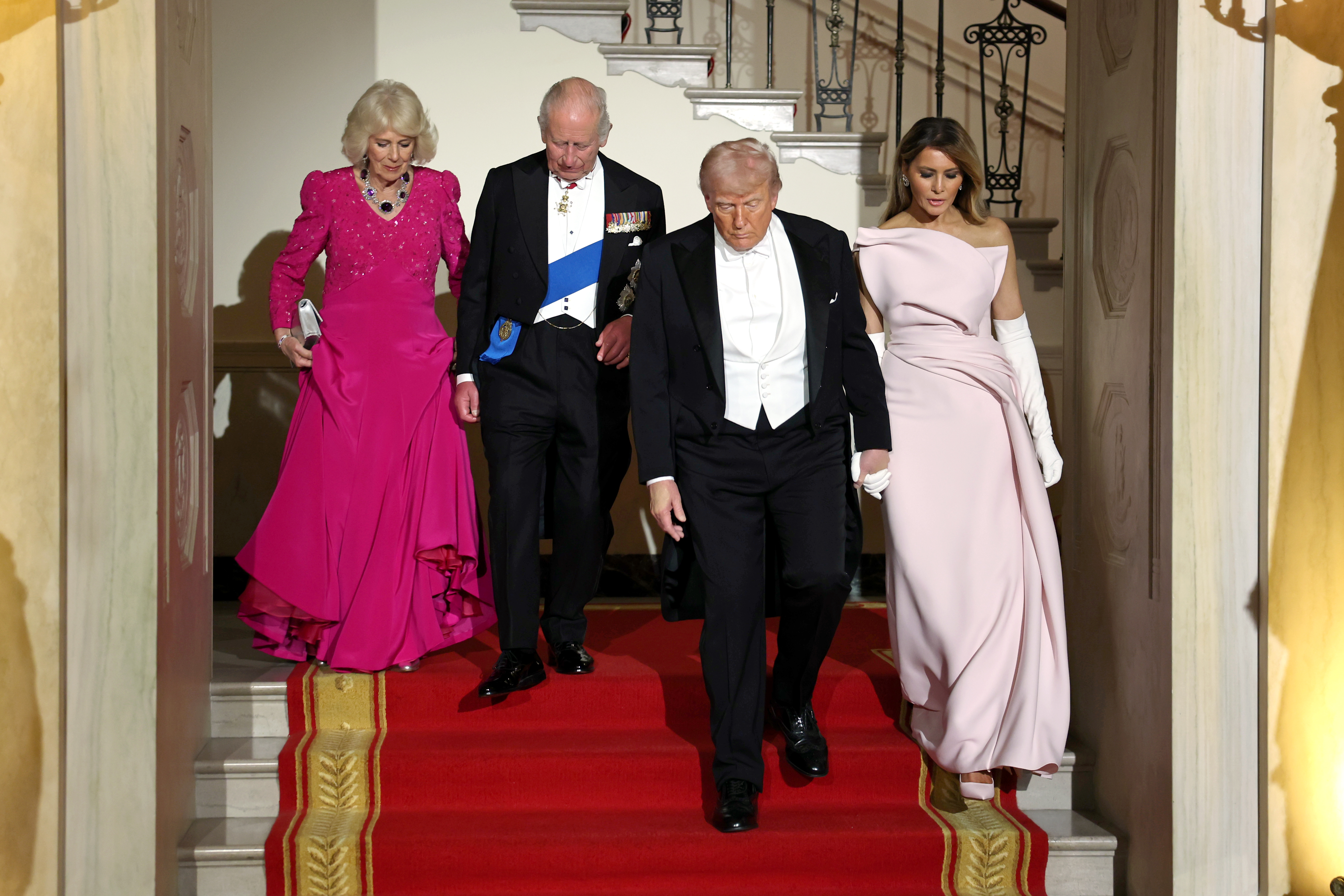 Queen Camilla, King Charles, Donald and Melania Trump in evening outfits walking down a staircase