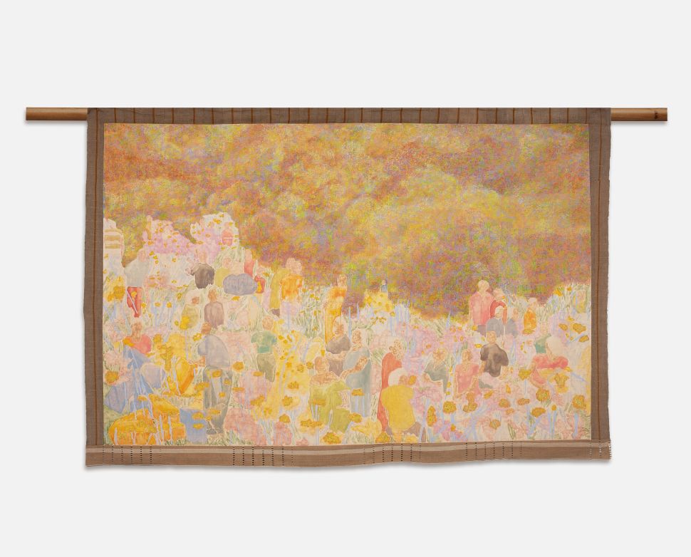 A large pastel-toned textile painting filled with small human figures and flowering plants beneath a hazy sky is suspended from a wooden support.