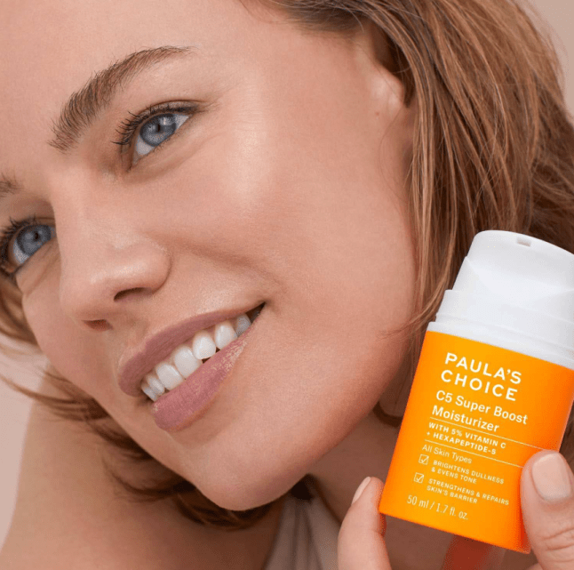 Female poses with orange product with white lid