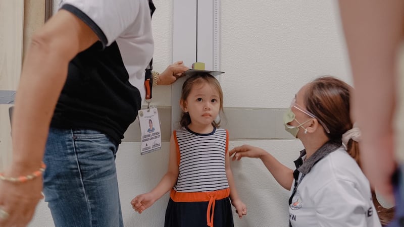 Health workers measure a child's height during a screening in Cebu City, Philippines, on Aug. 16, 2022.