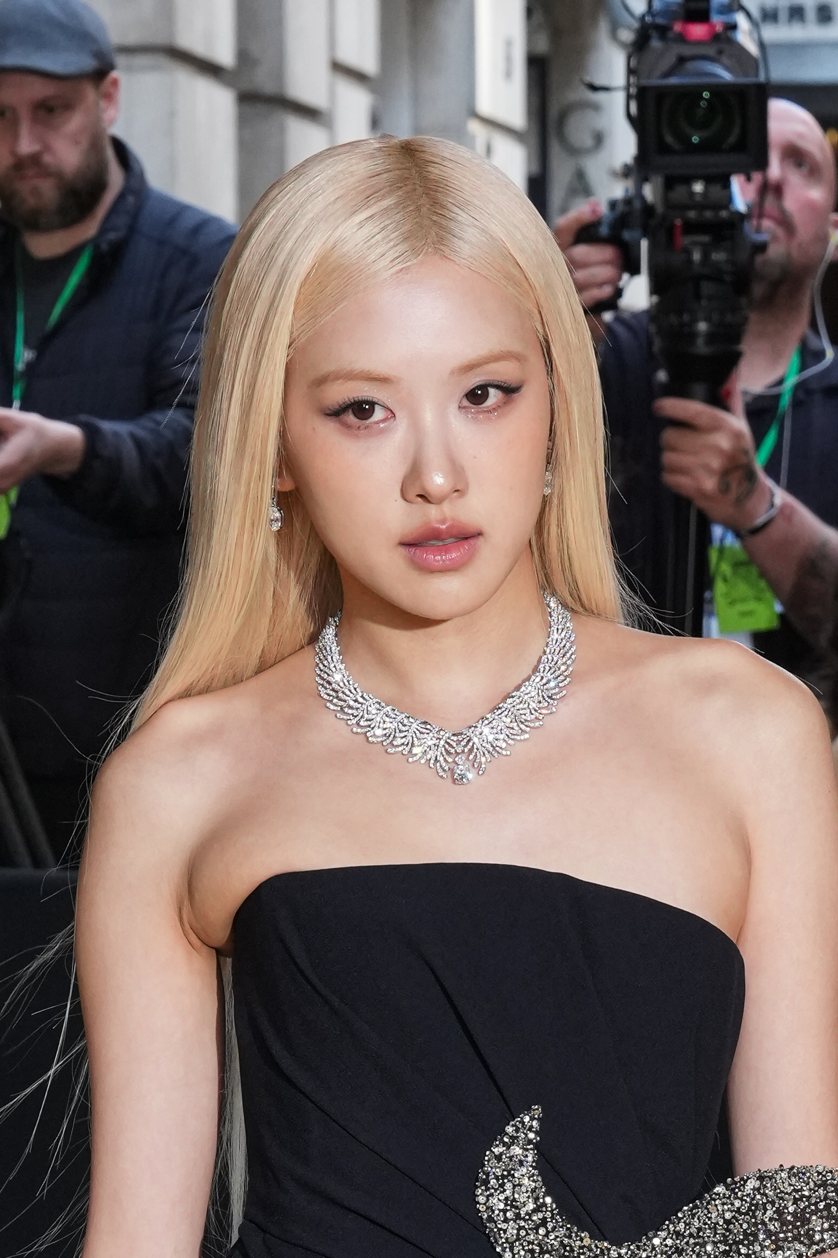 a blonde woman in a black dress with a diamond necklace