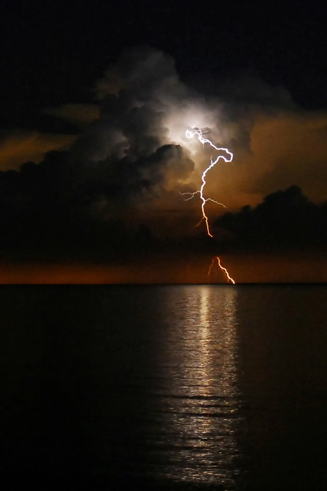 A lightning bolt pierces the clouds, reaching into the water of Lake Erie.