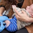 Baby getting vaccinated from his first vaccines. The doctor is giving him an injection while his mother is holding him in her arms.