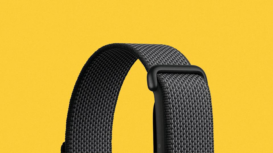 Black woven nylon watch strap with a black plastic loop on a yellow background.