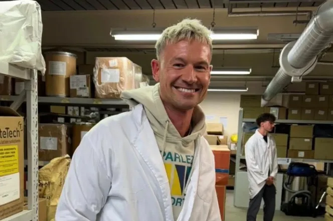 Kristian Trend smiling in a white lab coat inside a warehouse.