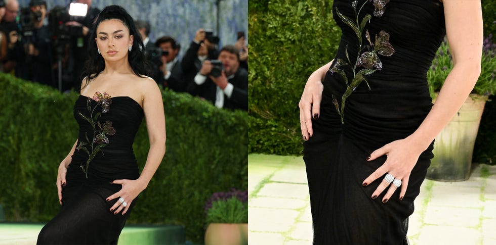Fashionable figure in a black dress with floral embellishments at a public event.