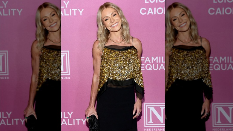 Kelly Ripa smiles in a gold sequin top and black skirt.