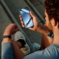 Man wearing Google Fitbit Air looking at his smartphone