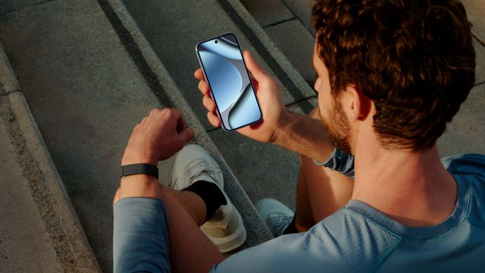 Man wearing Google Fitbit Air looking at his smartphone