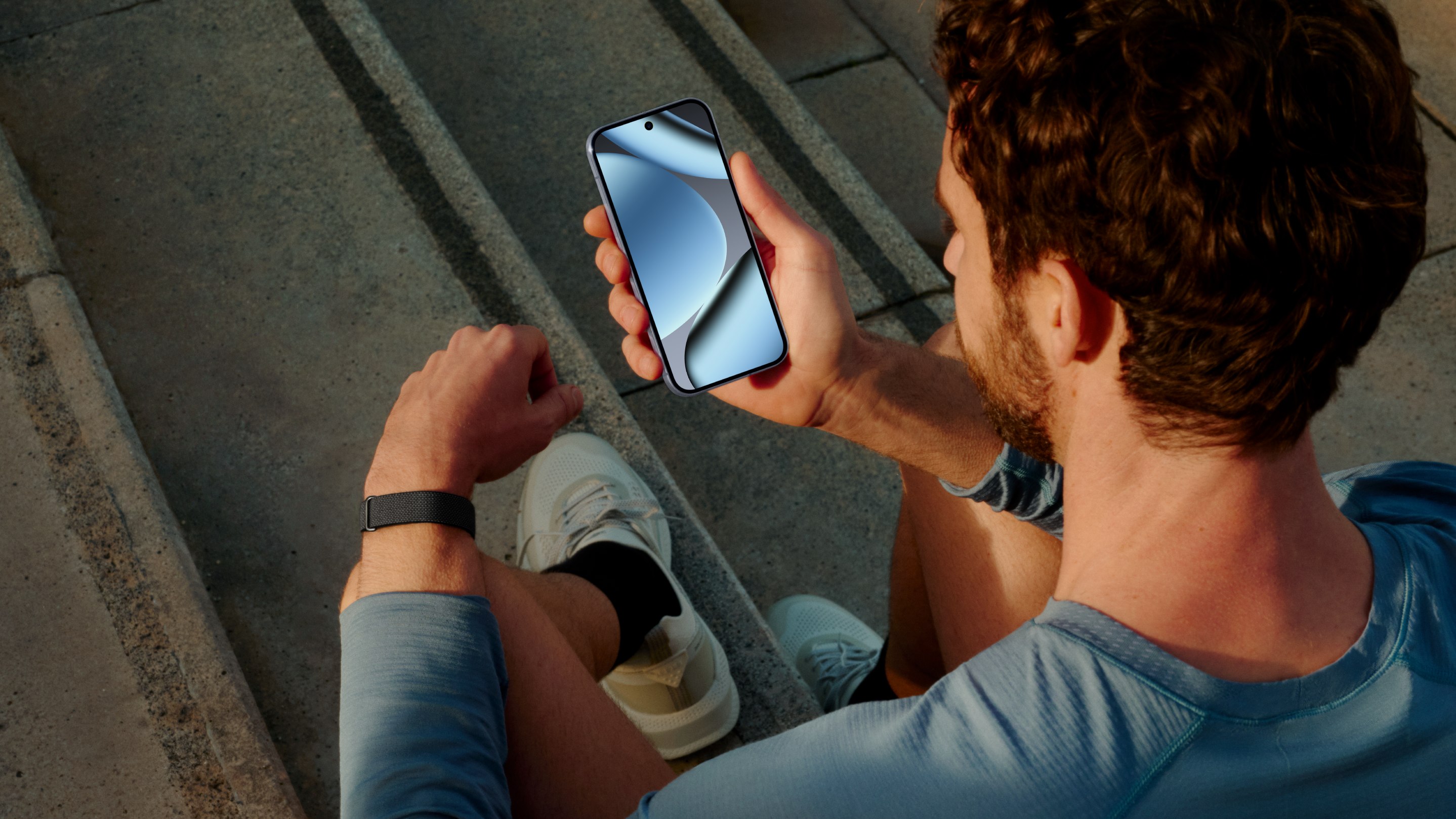 Man wearing Google Fitbit Air looking at his smartphone
