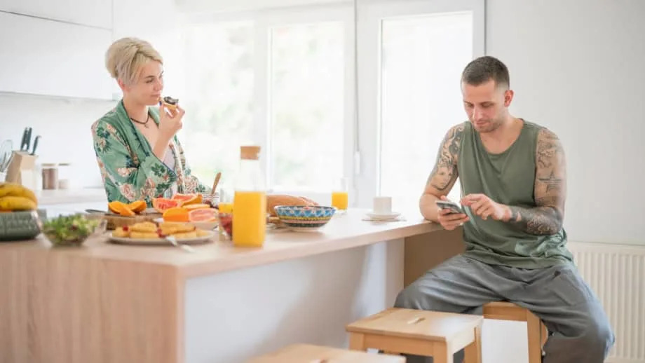 a man on a phone at the breakfast table