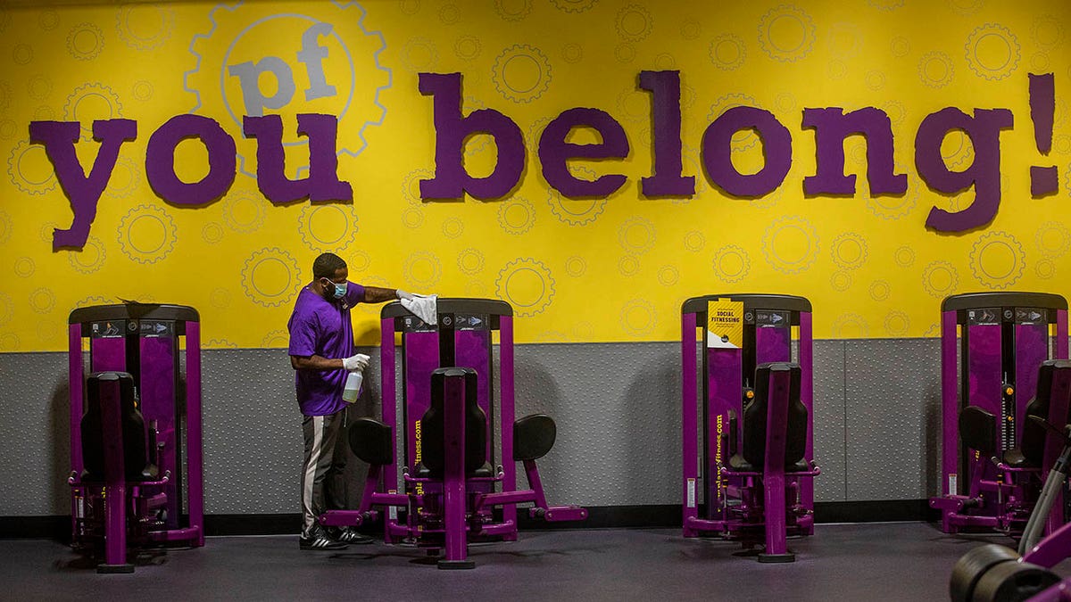 Anthony Carthan disinfecting exercise equipment inside Planet Fitness in Inglewood