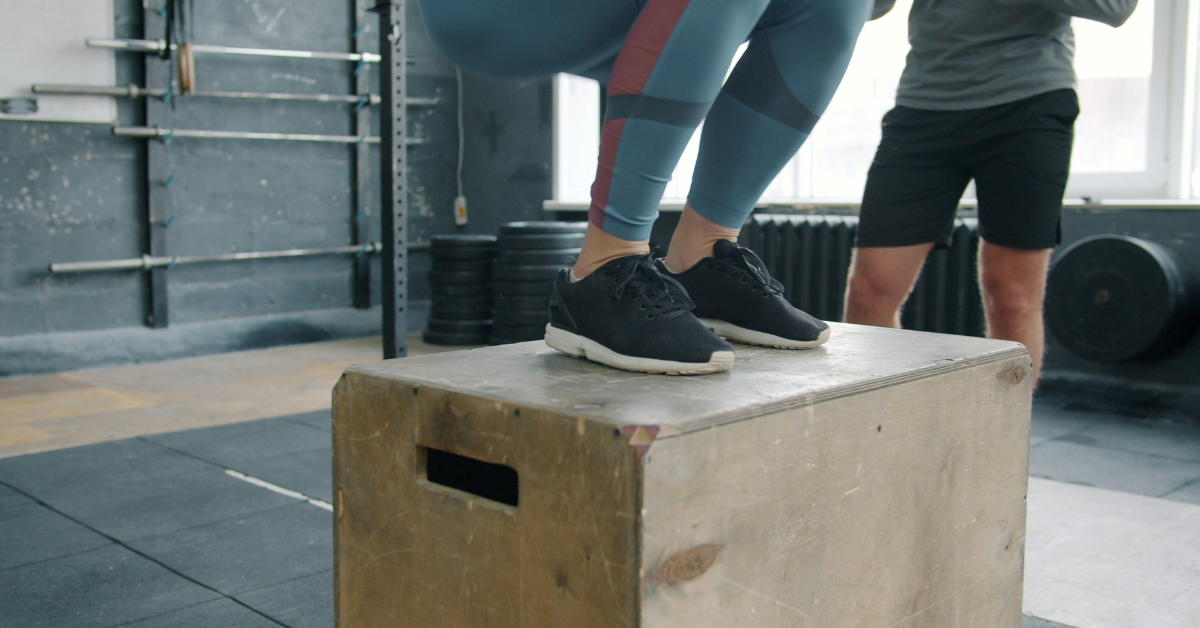 A person completes a box jump in a gym