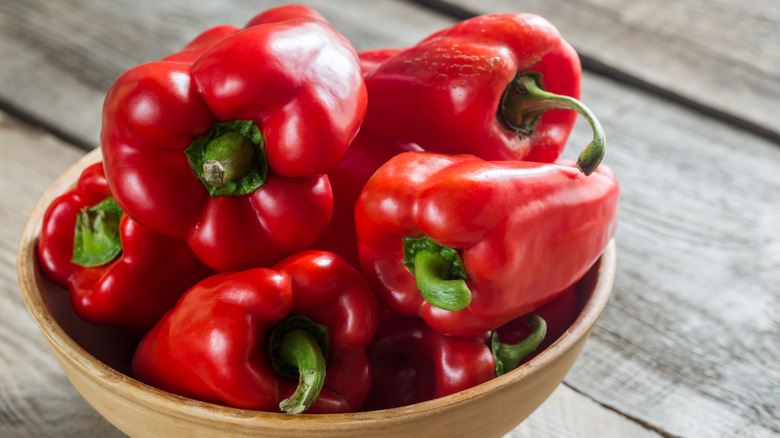 Wooden bowl filled with whole red bell peppers