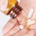 Vitamin B12 supplements being poured into a person’s hand from a brown bottle