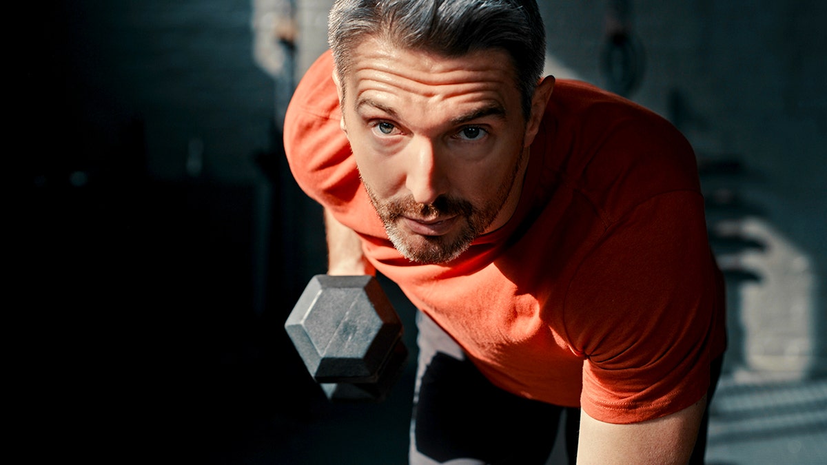 A mature man lifting dumbbells during a gym workout