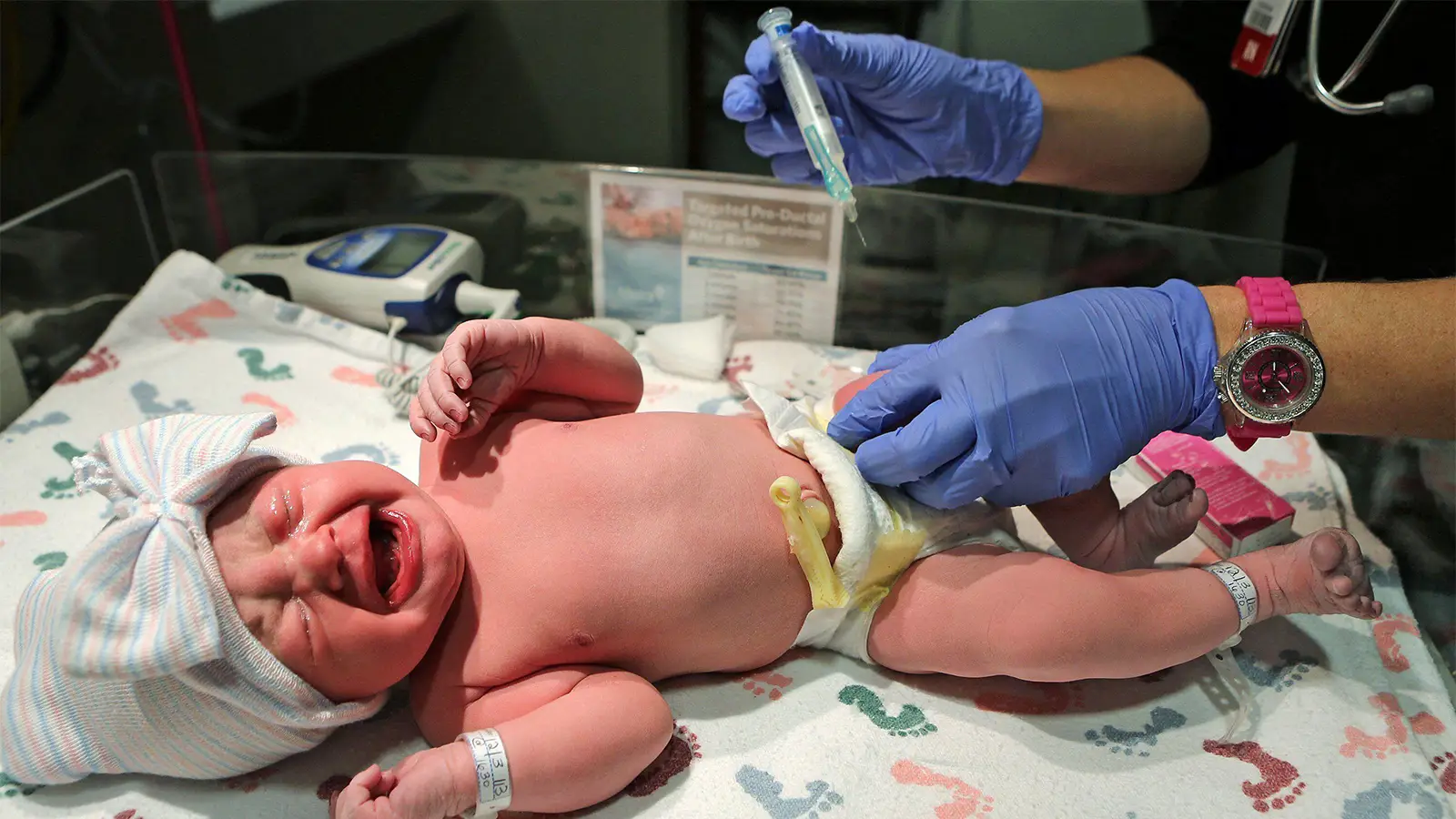 A photo of a female nurse giving an infant a vitamin K shot.