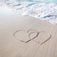 Two hearts drawn on a white sand beach.