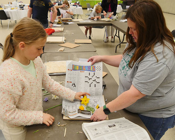 woman helping little girl with a craft project at a long table