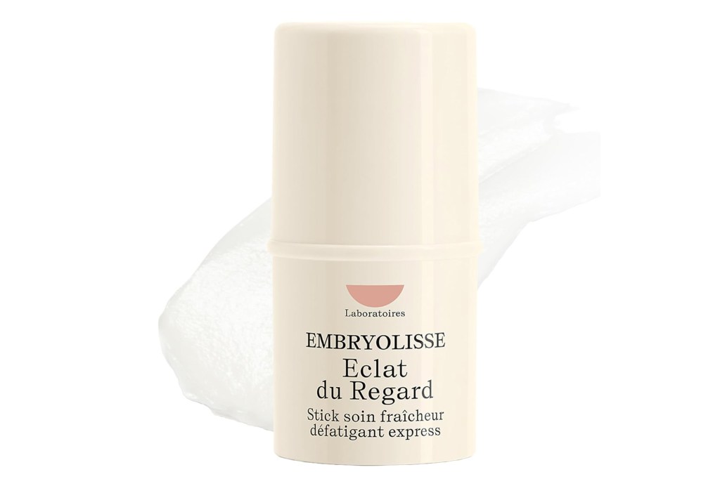 An off-white container of Embryolisse Eclat du Regard eye brightener with a swatch of the product on a white background.